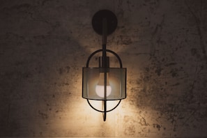 Eine wandmontierte Leuchte mit zylindrischem Lampenschirm und runder Basis.
