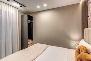 Moderni hotellihuone, jossa on sänky, vaatekaappi ja yöpöytä.