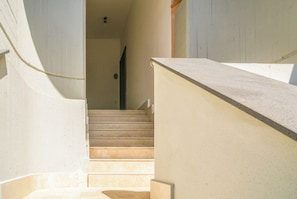 A staircase leading to a landing with a handrail on the right and a wall on the left. - Casa Eos (Torre A Mare)
