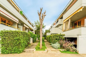 A courtyard with a central tree, surrounded by neatly trimmed hedges and a pathway. - Casa Eos (Torre A Mare)