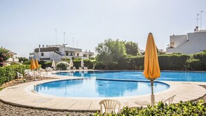 A swimming pool with lounge chairs and umbrellas, surrounded by greenery and buildings. - Casa Eos (Torre A Mare)