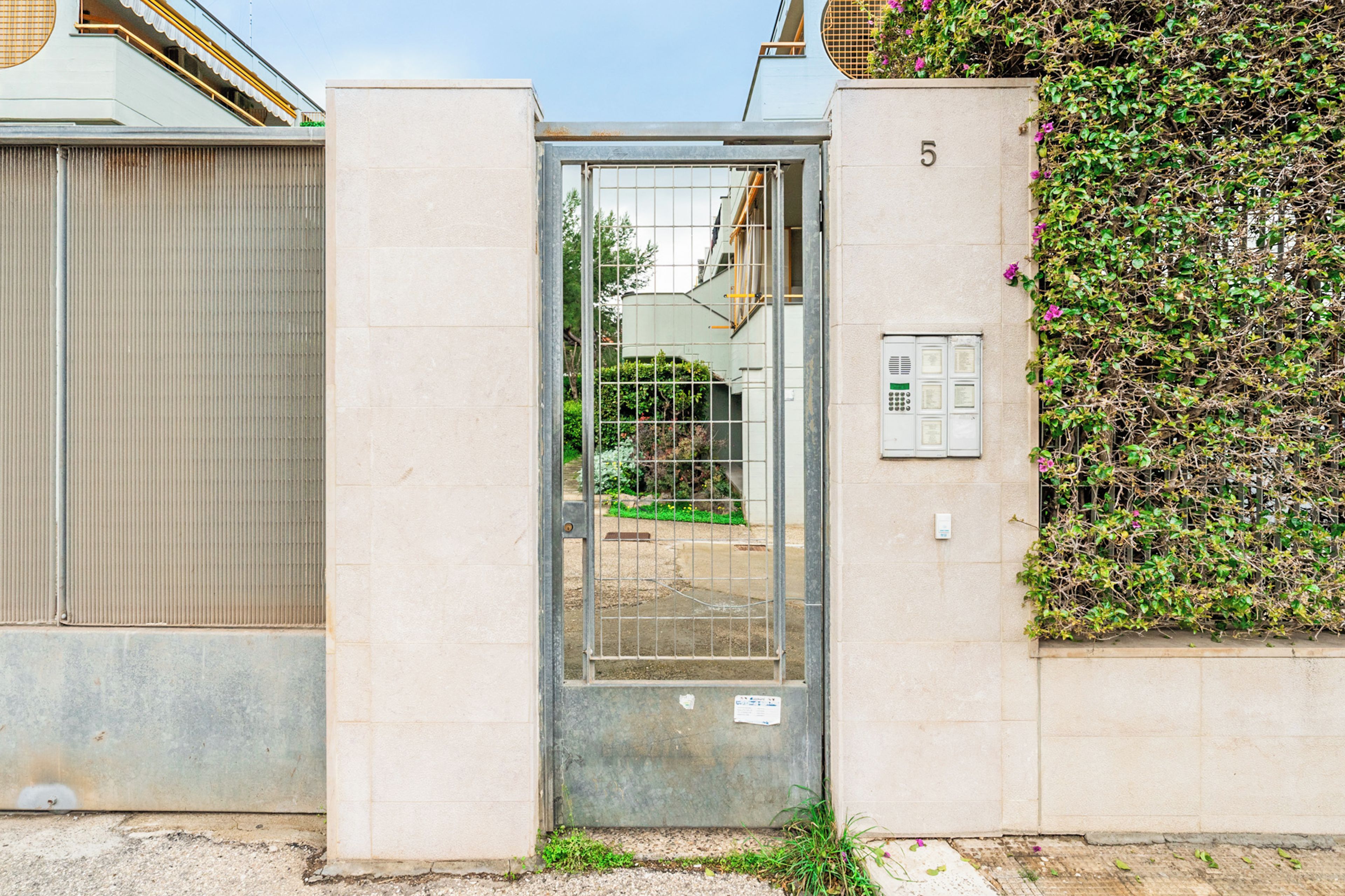 A gated entrance with a metal gate, a number '5' on the wall, and a utility box.