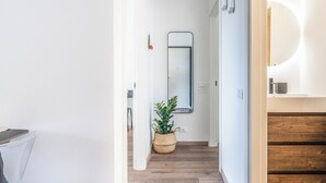 A hallway with a wooden floor, a potted plant, a mirror, and a wooden staircase. - Casa Eos (Torre A Mare)