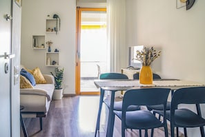 A modern living space with a dining area, a sofa, a coffee table, and a TV. - Casa Eos (Torre A Mare)