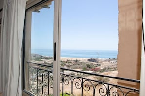 A balcony with a metal railing overlooking a beach and construction site.