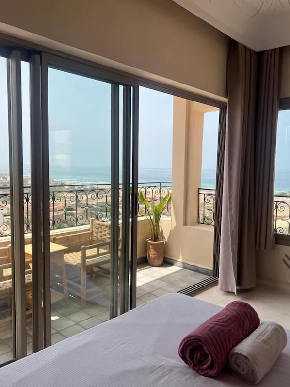 A hotel room with a large sliding glass door leading to a balcony with a view of the ocean.