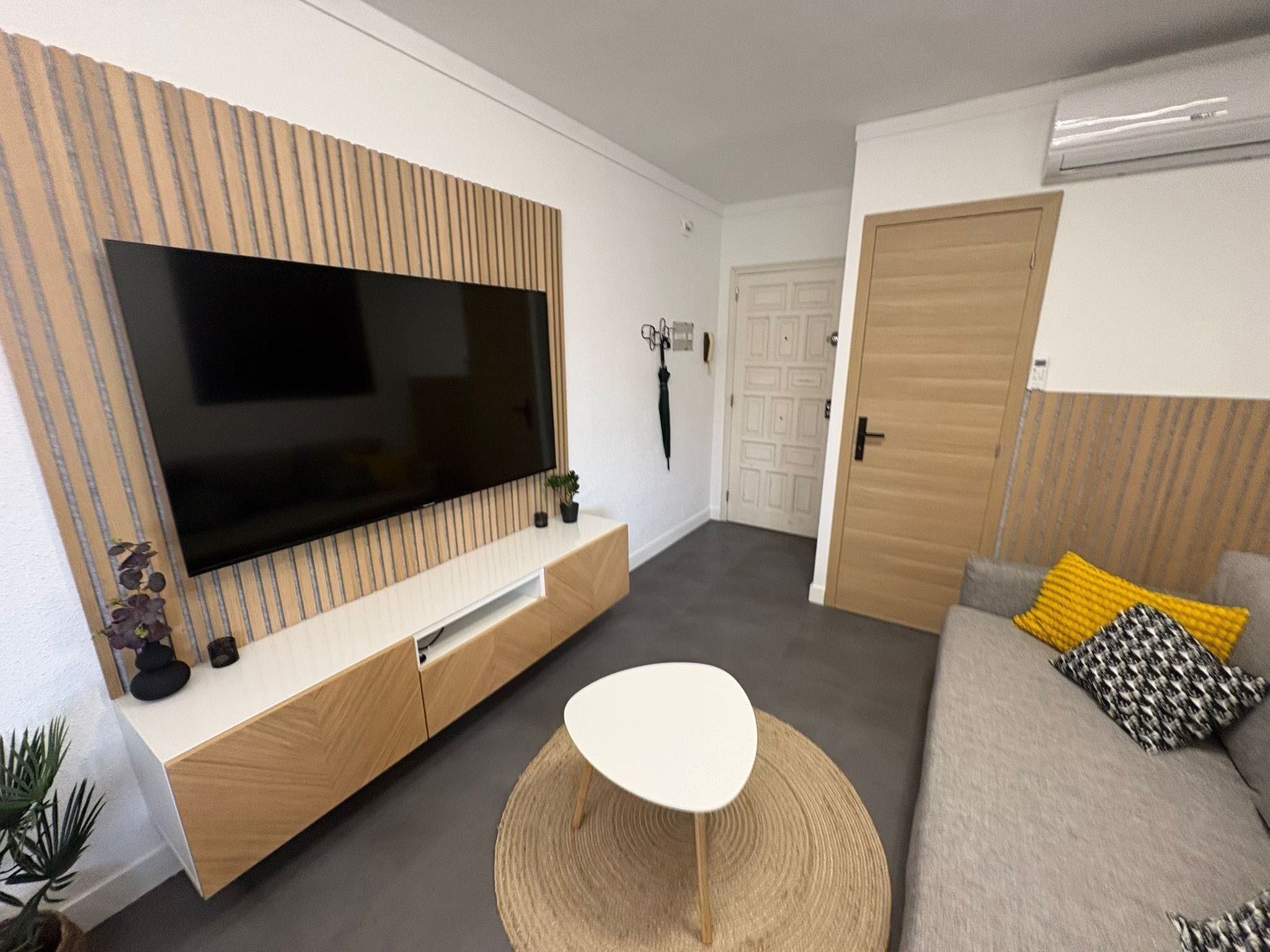 Un salon moderne avec un téléviseur à écran plat, un canapé, une table basse et une porte.