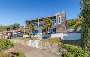 Een modern huis met twee verdiepingen, een stenen inkomhal, een trap en een heldere lucht.