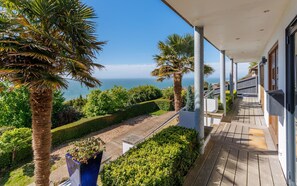 A balcony with a view of the sea, surrounded by palm trees and a wooden deck. - Kittiwake (Ventnor)