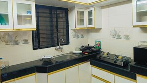 A kitchen with white cabinets, a black countertop, a gas stove, and a window with a black grill.