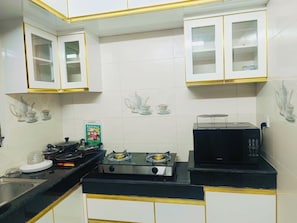 A kitchen with white cabinets, a gas stove, a microwave, and a sink.