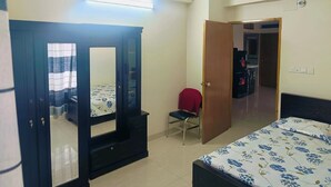 Ein Schlafzimmer mit Bett, Schrank, Stuhl und einer Tür zu einem anderen Raum.