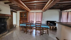 A dining area with a table, chairs, a fireplace, and a television. - Gite l'écurie, in a restored farmhouse, fully equipped with pellet stove (Surtainville)
