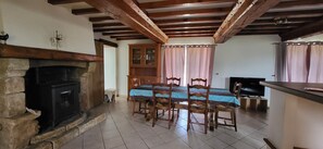 A dining area with a table, chairs, a fireplace, and a television.