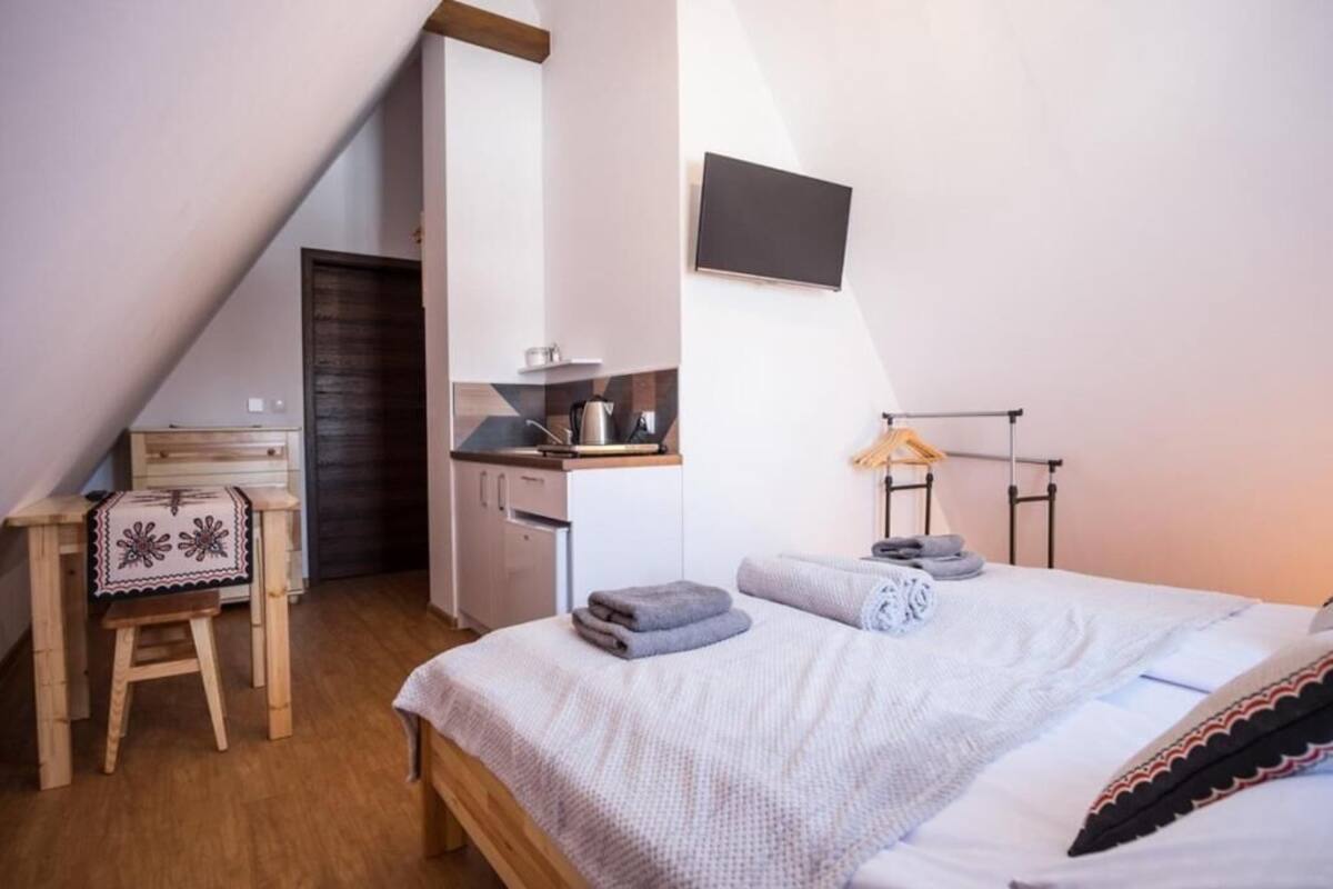 Ein Schlafzimmer mit Bett, Schreibtisch, Sessel, Fernseher und Kleiderschrank.