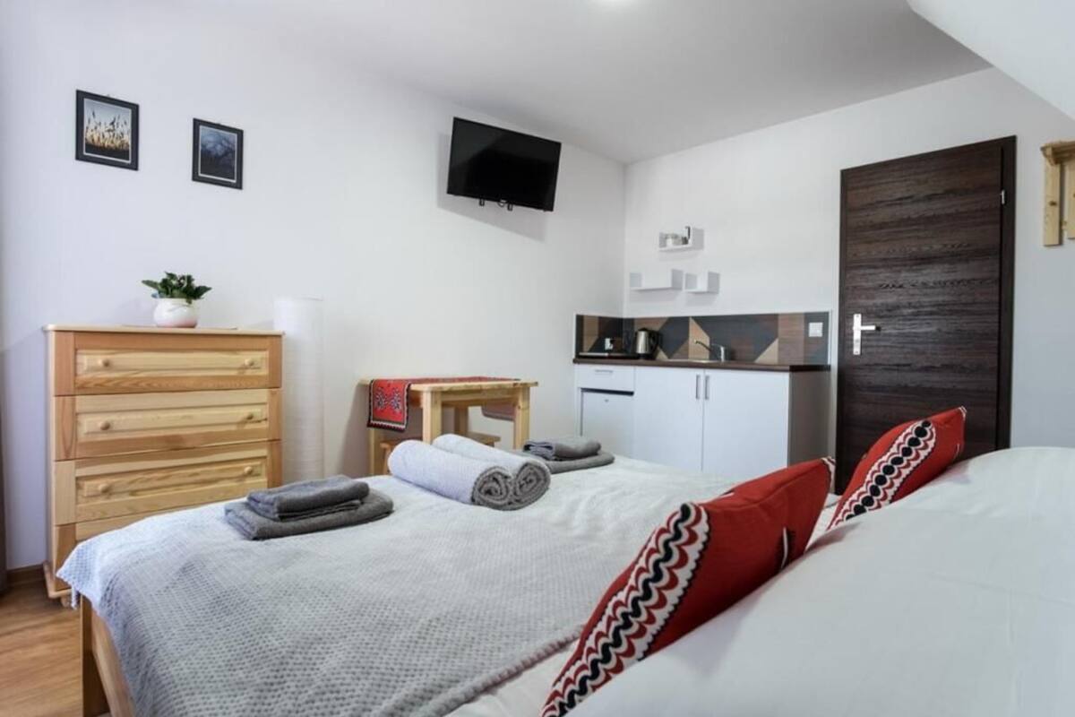 Ein Schlafzimmer mit einem Bett, einem Schminktisch, einem kleinen Tisch, einem Fernseher und einer Tür.