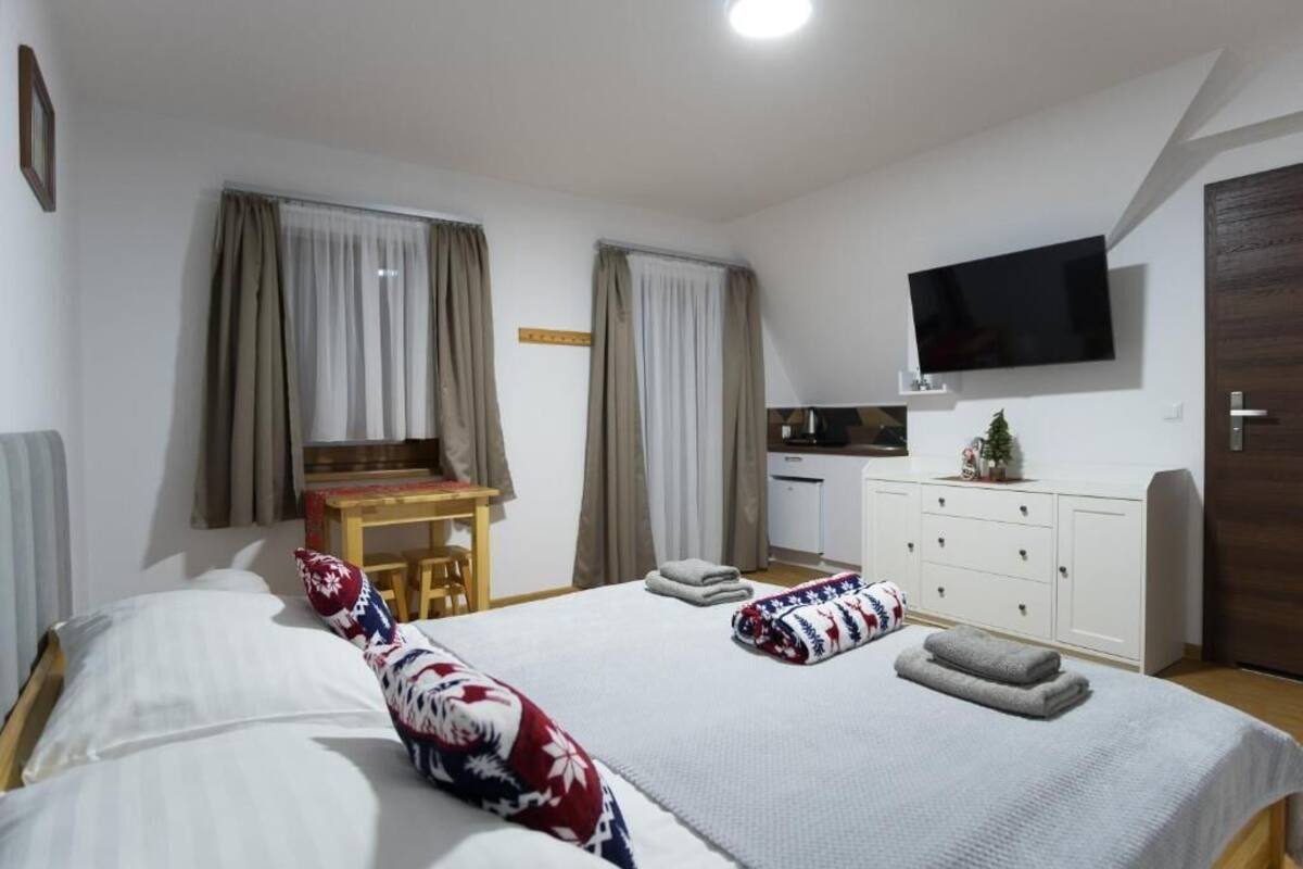 Ein Schlafzimmer mit zwei Betten, einem Schreibtisch, einem Fernseher und einem Kleiderschrank.