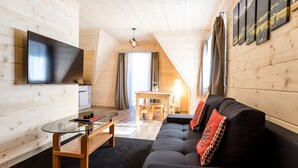 Una habitación acogedora con sofá, televisión, mesa de comedor y ventana con cortinas.