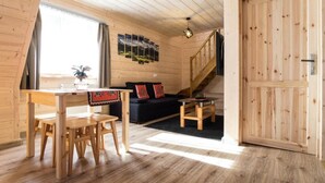 Un interior de madera con una mesa de comedor, sillas, un sofá, una escalera y una puerta.