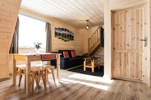 Un interior de madera con una mesa de comedor, sillas, un sofá, una escalera y una puerta.