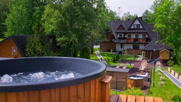 Un jacuzzi, una terraza de madera y una casa con techo inclinado.