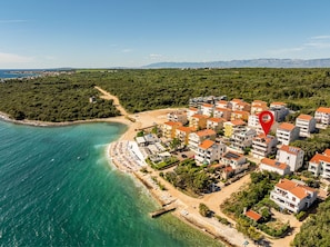 Eine Luftaufnahme einer Küstenwohngegend mit Gebäuden, einem Strand und einer Bergkulisse.