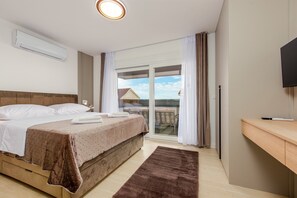 Ein Schlafzimmer mit Bett, Flachbildfernseher, Balkon mit Blick und Klimaanlage.
