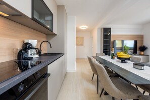 Eine moderne Küche mit Einbauherd, einer Essecke mit langem Tisch und Stühlen sowie einem großen Flachbildfernseher, der über dem Tisch angebracht ist.