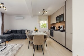 Ein moderner Wohnraum mit Essbereich, Küche und einem großen Fenster.