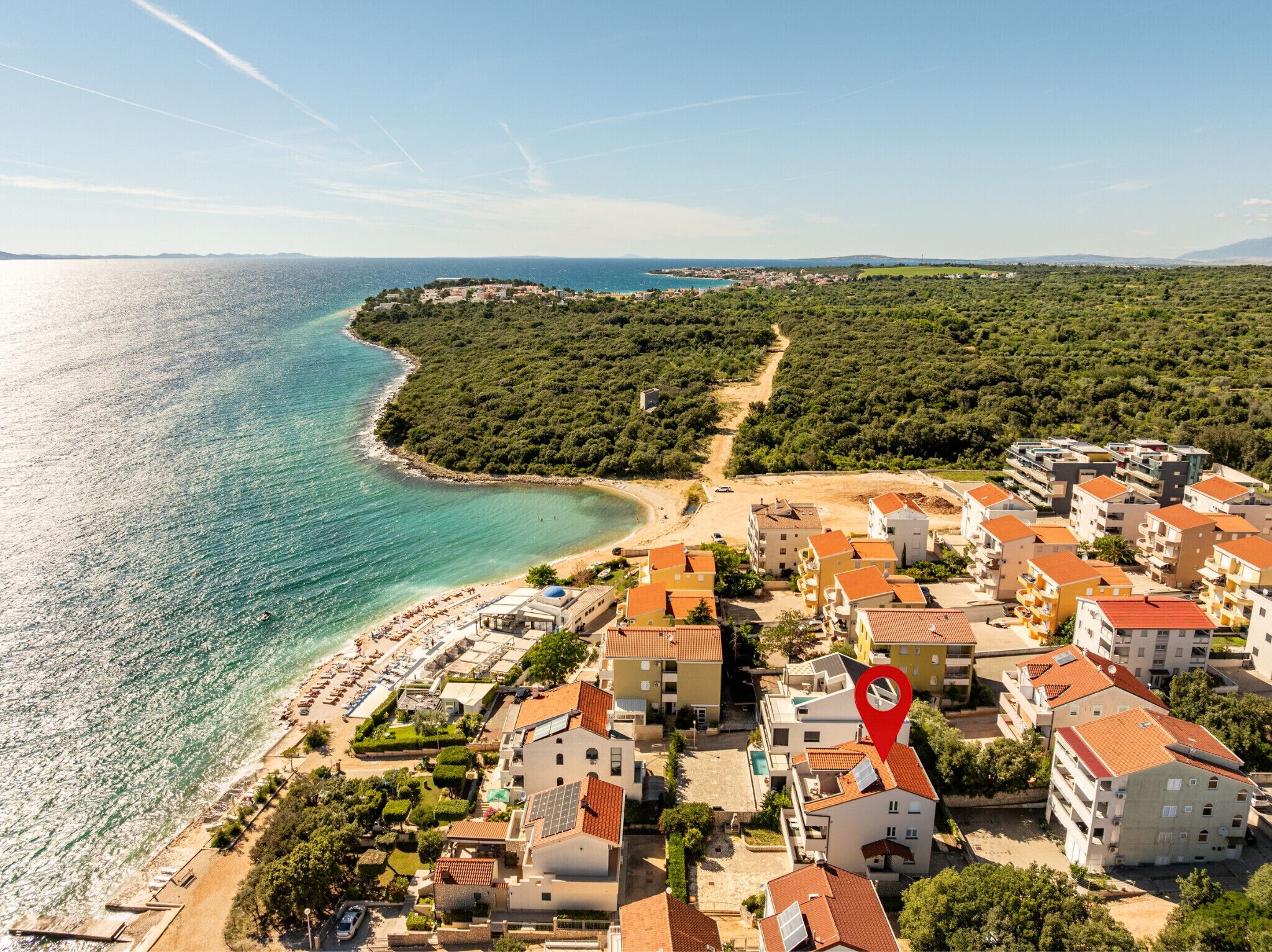 Un pueblo costero con playa, edificios residenciales y un lugar señalado.