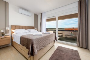 Ein Hotelzimmer mit Bett, Nachttisch, Fenster mit Aussicht und einem Balkon.