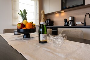Eine Champagnerflasche, eine Obstschale und ein Glas auf einem Tisch in einer modernen Küche.