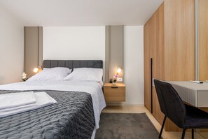 Ein modernes Hotelzimmer mit einem Bett, Nachttischen, einem Schreibtisch und einem Sessel.