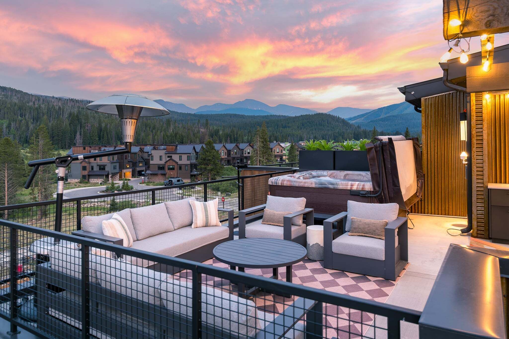 A rooftop terrace with outdoor seating, a large umbrella, and a mountain view.