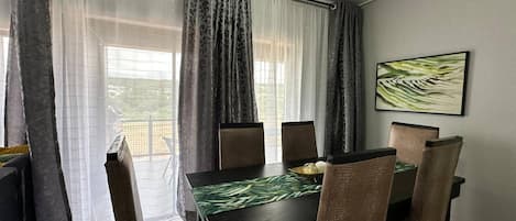 A dining area with a table, chairs, and curtains.