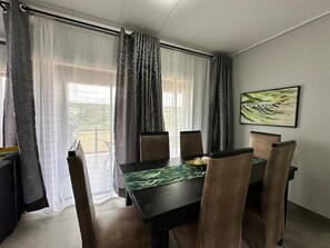 Ein Essbereich mit Tisch, Stühlen und Vorhängen.