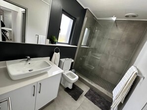 Un baño moderno con lavamanos, inodoro y ducha blancos.