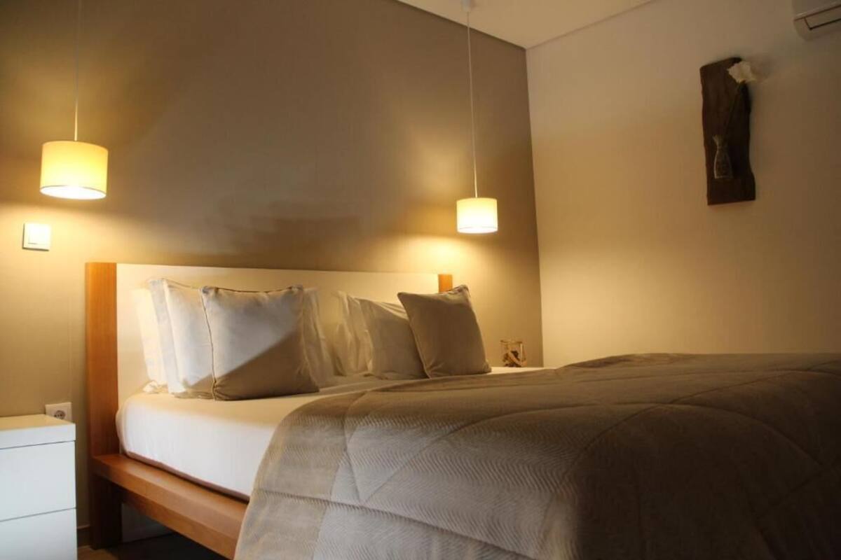 Ett hotellrum med en säng, sängbord och två hängande lampor.