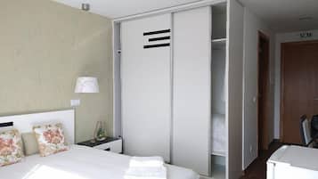 Ein Schlafzimmer mit Bett, Kleiderschrank, Nachttisch und Lampe.
