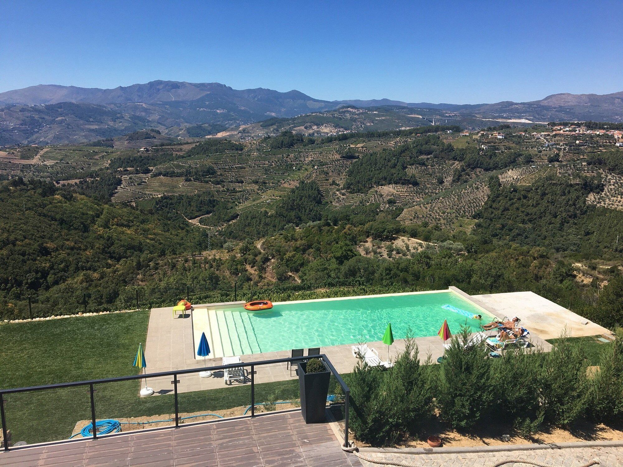 A pool with clear water, surrounded by greenery and a view of distant mountains.