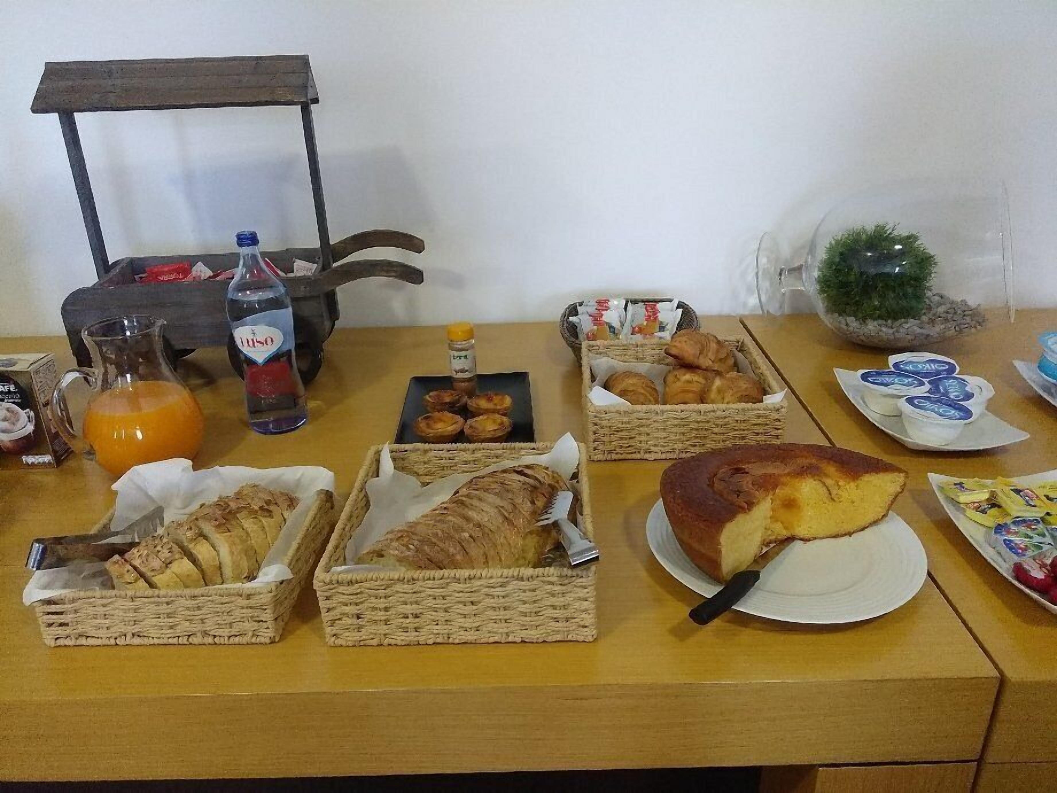A breakfast table with bread, pastries, juice, and a bottle of water.