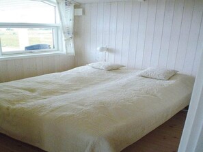 A single bed with a white duvet, a bedside lamp, and a window with curtains. - 4 Star Holiday Home in Rudkobing (Rudkobing)