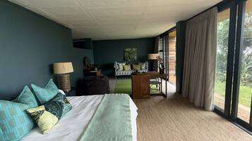 Un dormitorio con cama, escritorio y vista al verde exterior.