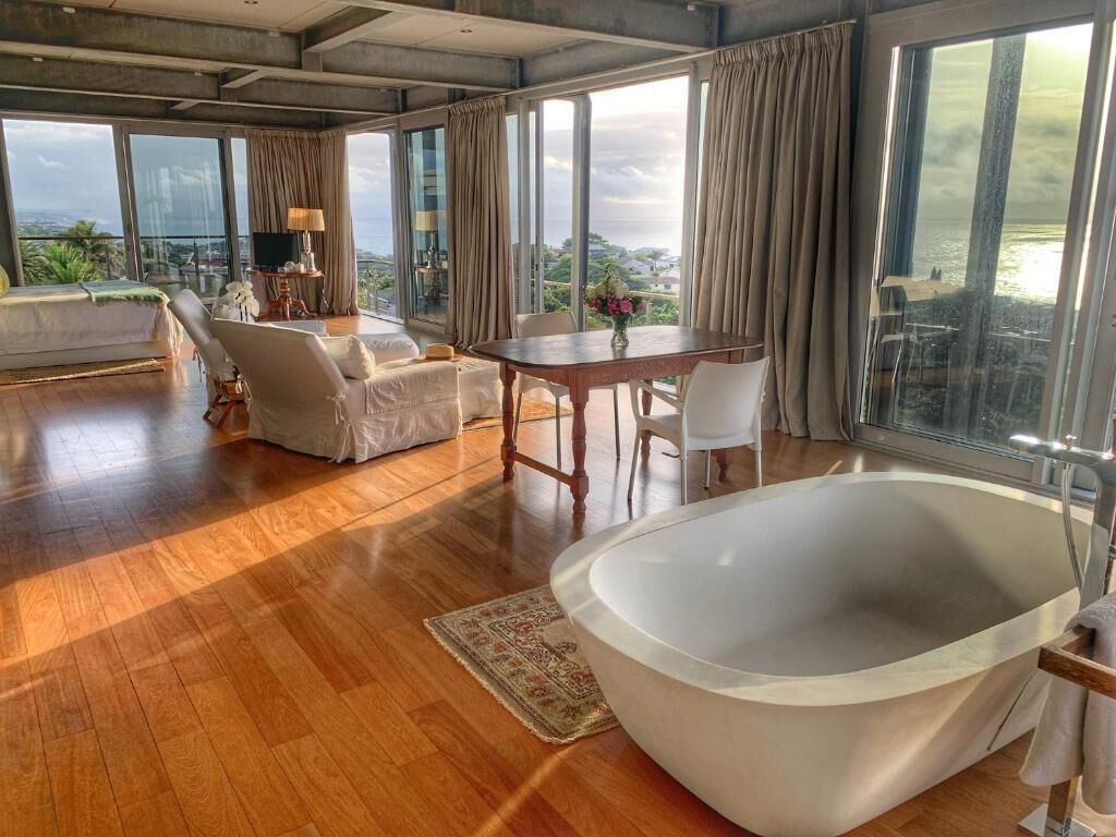 Quarto espaçoso com uma banheira grande, área de jantar e sofá.