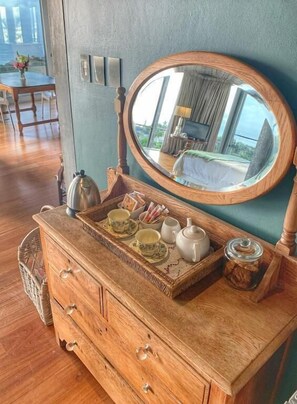 A wooden dresser with drawers, a mirror, and a tray with cups and a teapot.