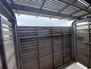 Una habitación con un separador de madera, una puerta de metal y un techo con estructura de rejilla.