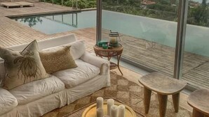 A modern interior with a sofa, a round table with candles, and a view of a pool and landscape. - The Seaglass (Durban)