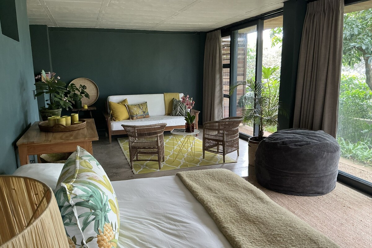 Una habitación con cama, sofá, mesa de comedor con velas y un ventanal con cortinas.