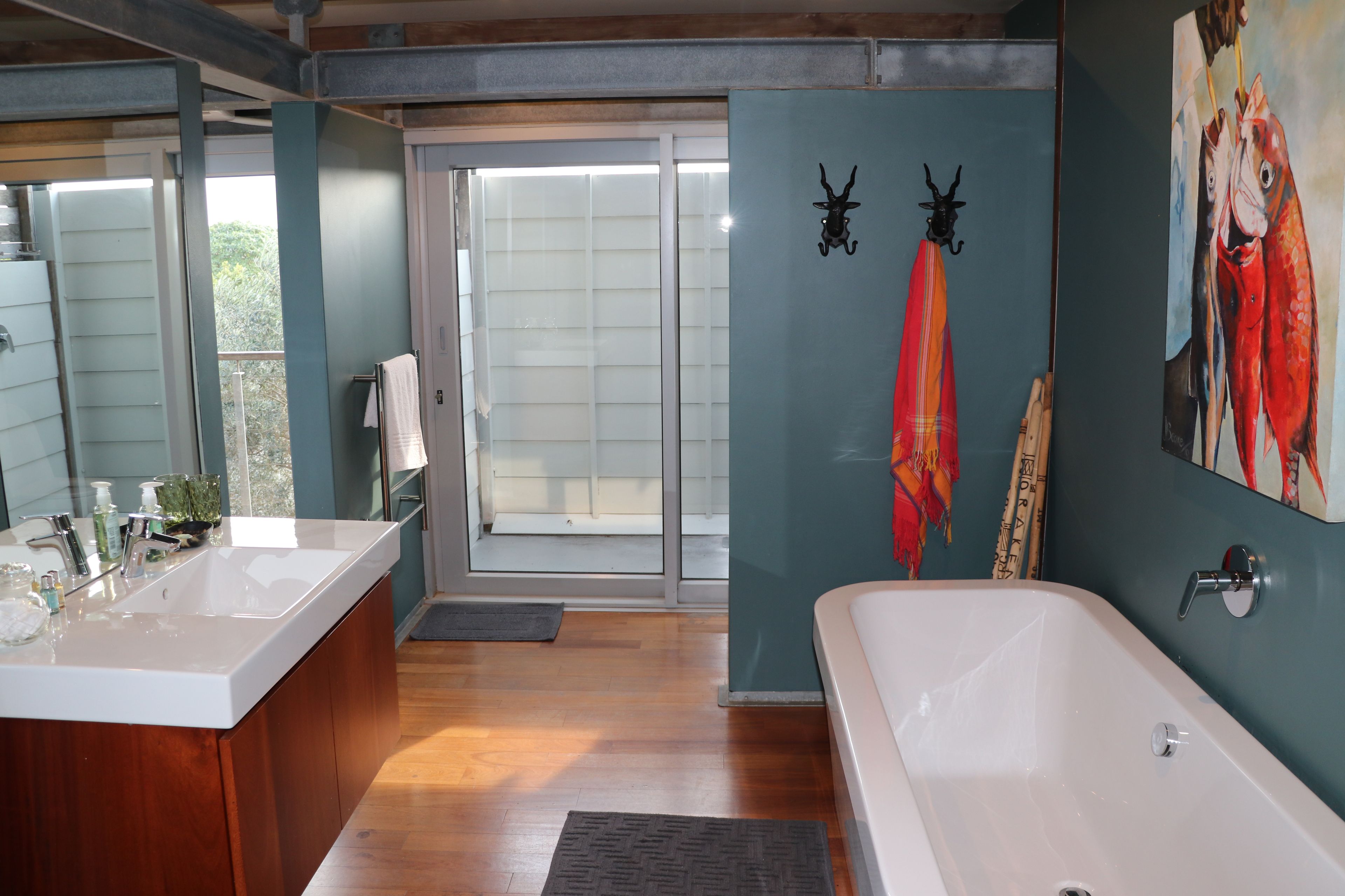 A bathroom with a bathtub, a sink, and a mirror. There is a door leading to an outdoor area.