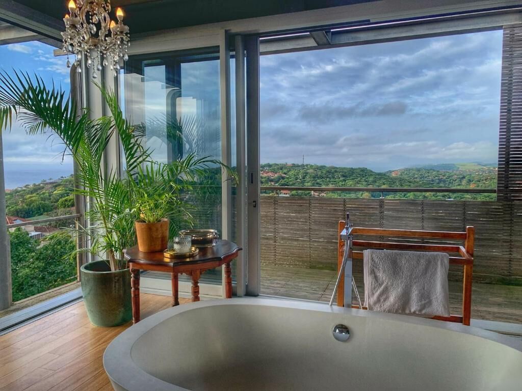 Un baño moderno con una bañera grande, una silla de madera y una mesa con una planta en maceta.